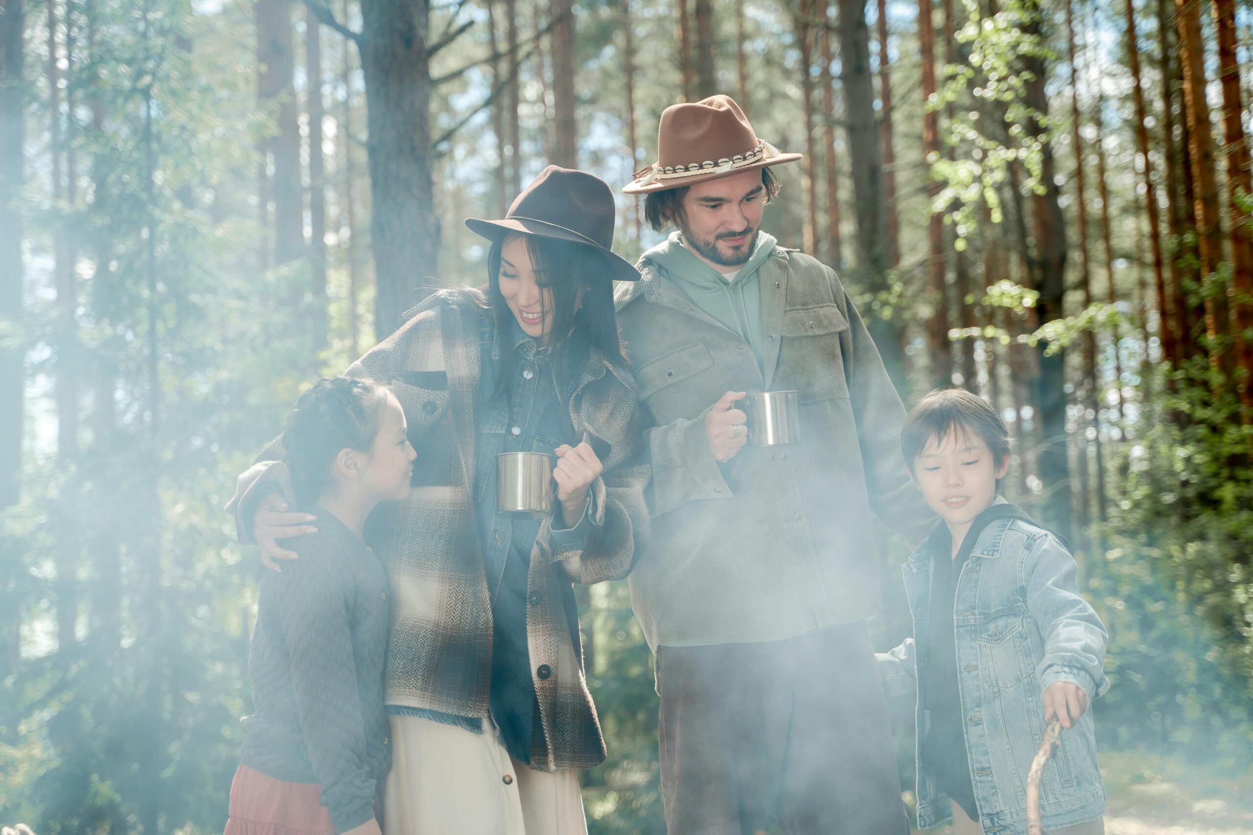Happy family bonding during a nature walk in a sunlit forest with misty ambiance.